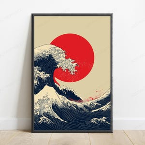 May include: A rectangular wall art print in a black frame featuring a stylized illustration of a large, dark blue ocean wave with white foam crests. A solid, vibrant red circle is positioned in the upper center against a light beige background.