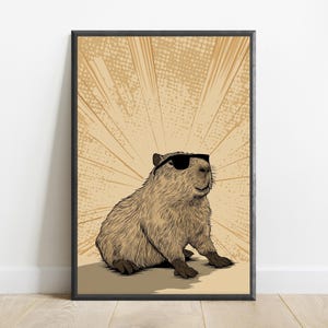 May include: A framed wall art print featuring a detailed illustration of a brown capybara wearing black sunglasses. The background consists of a light tan color with radiating sunburst lines and a subtle dot pattern, all enclosed in a black frame.