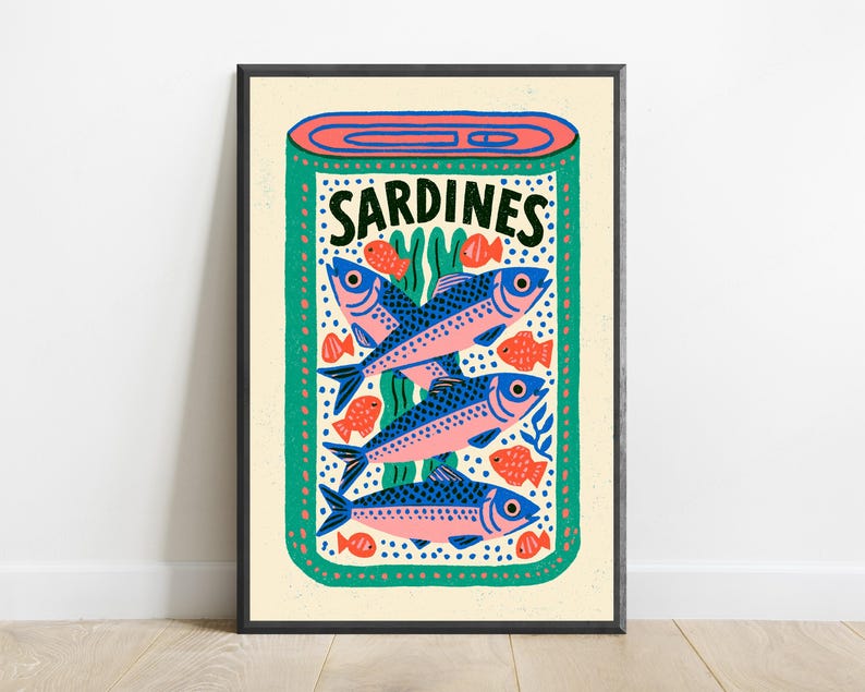May include: A rectangular wall art print featuring a stylized illustration of an open tin of sardines. The design includes three large blue and pink fish, several smaller orange fish, and green seaweed accents on a cream background with the text SARDINES.