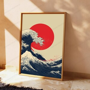 May include: A rectangular framed wall art print featuring a stylized dark blue ocean wave with white foam crests set against a solid cream background. A large, solid red circle is positioned behind the wave, mimicking a rising sun.