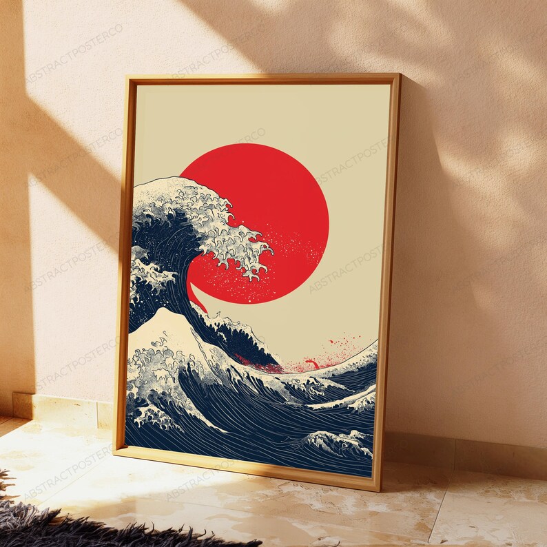 May include: A rectangular framed wall art print featuring a stylized dark blue ocean wave with white foam crests set against a solid cream background. A large, solid red circle is positioned behind the wave, mimicking a rising sun.