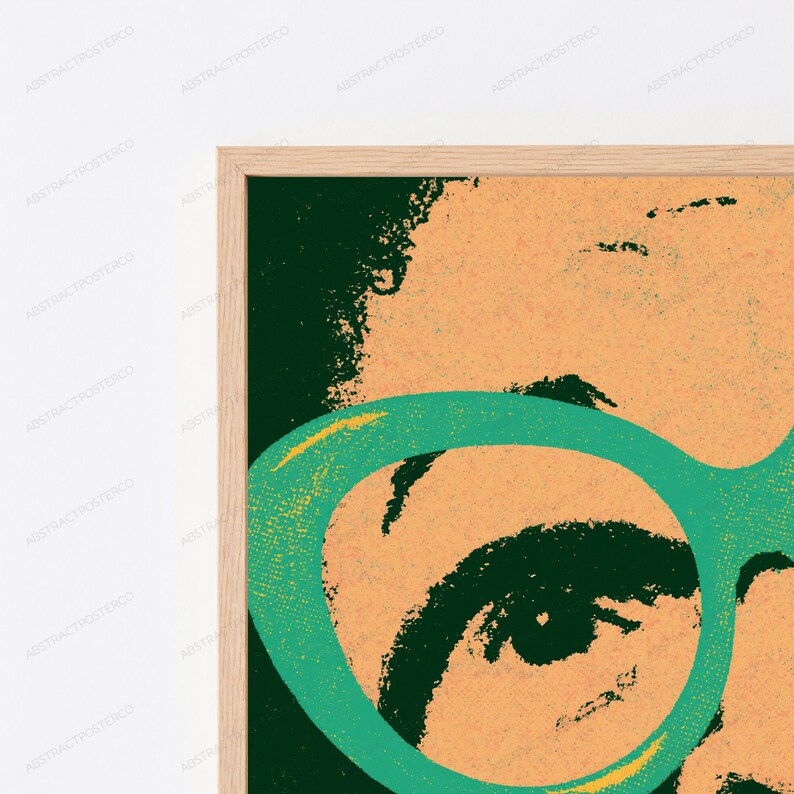May include: A framed wall art print featuring a stylized, high-contrast graphic illustration of a face. The image uses a color palette of dark forest green, peach, and bright teal, showcasing a large teal eyeglass frame over one eye.