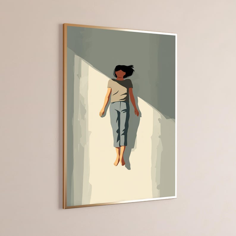 May include: A framed wall art print featuring a stylized illustration of a person with dark hair lying flat on a light-colored surface. The person wears a beige short-sleeved shirt and blue pants, positioned within a sharp, angular shadow.