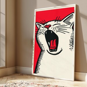 May include: A framed wall art print featuring a stylized illustration of a white cat with its mouth wide open in a yawn. The cat is depicted with bold black outlines against a vibrant red background, showcasing its teeth, tongue, and whiskers.