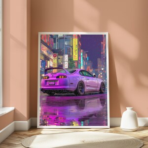 May include: A framed vertical art print depicting a purple sports car parked on a wet city street at night. The scene features vibrant neon signs in the background and a clear reflection of the vehicle on the rain-slicked pavement surface.