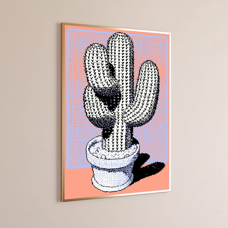 May include: A framed wall art print featuring a pixelated black and white cactus in a white pot. The background is a light blue rectangle set against a solid peach-colored field. The cactus has a distinct shadow cast to the right side.