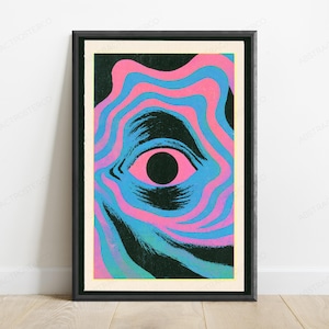 May include: A framed rectangular wall art print featuring a central black pupil surrounded by a pink iris. The eye is set against a background of wavy, concentric bands of alternating bright pink and cyan blue, with dark textured brushstroke accents.