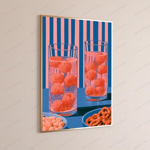 May include: A framed vertical wall art print featuring two tall glasses filled with sparkling liquid and floating raspberries, set against a background of vertical pink and blue stripes. Below the glasses are two bowls containing snacks.