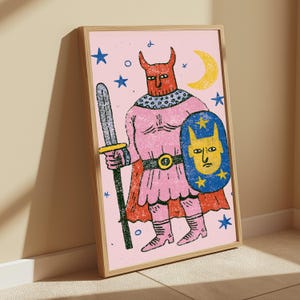 K&ouml;nnte beinhalten: Ein gerahmter Kunstdruck mit einer texturierten Illustration einer geh&ouml;rnten Figur in rosa R&uuml;stung, die ein langes Schwert und einen blauen Schild mit einem gelben Gesichtsemblem h&auml;lt. Der Hintergrund ist hellrosa mit blauen Sternen und einem gelben Halbmond.