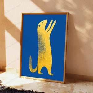 K&ouml;nnte beinhalten: Ein rechteckiger gerahmter Kunstdruck mit der stilisierten Silhouette eines gelben Erdm&auml;nnchens mit k&ouml;rnigem Textureffekt vor einem einfarbigen, tiefblauen Hintergrund. Das Erdm&auml;nnchen steht aufrecht mit erhobenen Vorderpfoten.