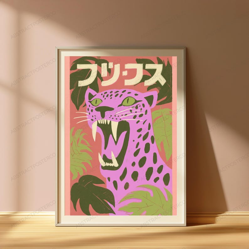 May include: A framed wall art print featuring a pink leopard with dark spots and green eyes, shown with its mouth open in a roar. The background is a salmon pink color with green tropical leaves and Japanese text at the top in white lettering.