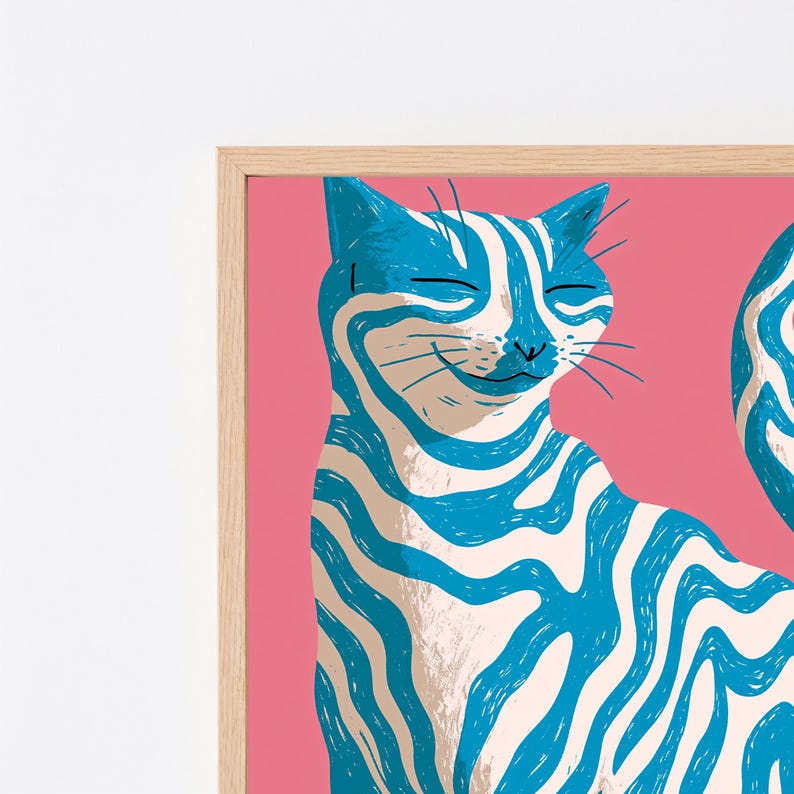 May include: A framed wall art print featuring a stylised cat with blue and white wavy stripes against a solid pink background. The cat has closed eyes and a subtle smile, rendered in a graphic illustration style within a light wood frame.