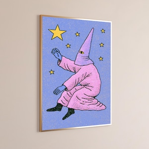 May include: A framed wall art print featuring a figure in a pink hooded robe with a single yellow eye on the hood. The figure has blue hands and black feet, set against a textured periwinkle blue background with several yellow stars of varying sizes.