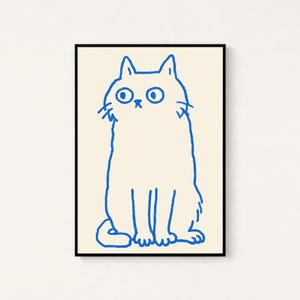 May include: A framed wall art print featuring a simple, hand-drawn illustration of a cat in bright blue ink on a cream-colored background. The cat is depicted in a seated position with wide, circular eyes and a small, minimalist facial expression.