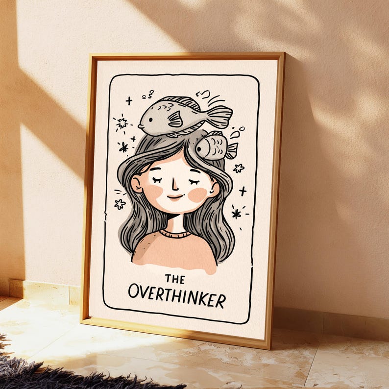 K&ouml;nnte beinhalten: Ein gerahmter Kunstdruck mit einer schwarz-wei&szlig;en Strichzeichnung einer Person mit langem Haar und zwei Fischen auf dem Kopf. Der Text THE OVERTHINKER ist unten aufgedruckt. Die Illustration verwendet einen cremefarbenen Hintergrund mit zartrosa Akzenten.