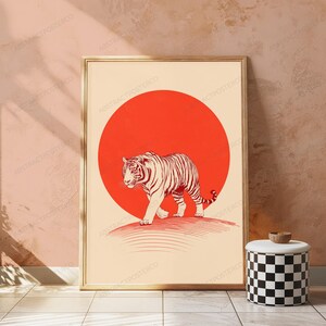 May include: A rectangular framed wall art print featuring a cream-coloured background with a large, solid red circle centred behind a detailed, line-art illustration of a tiger walking forward. The tiger is rendered in dark red ink lines.