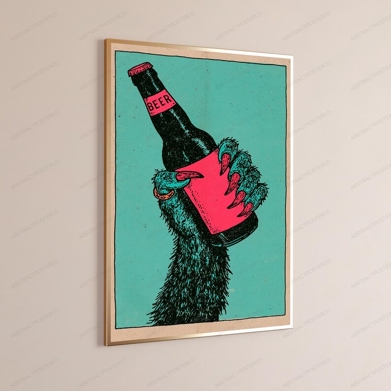 May include: A framed wall art print featuring a dark, furry creature hand with sharp claws holding a black beer bottle. The bottle has a pink label with the word BEER printed in black. The background is a solid teal colour with a black border.