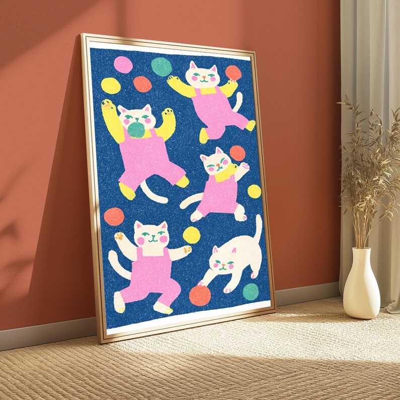 K&ouml;nnte beinhalten: Ein gerahmter vertikaler Kunstdruck mit f&uuml;nf wei&szlig;en Katzen mit rosa Wangen, die rosa Latzhosen tragen, vor einem texturierten dunkelblauen Hintergrund. Die Katzen sind in verschiedenen verspielten Posen dargestellt, umgeben von verstreuten bunten Kreisen in Gelb, Orange und Gr&uuml;n.