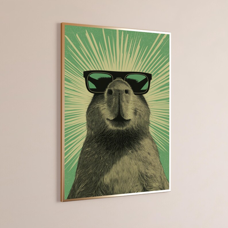 Peut inclure: Une impression d'art mural encadr&eacute;e repr&eacute;sentant une illustration d&eacute;taill&eacute;e d'un capybara portant des lunettes de soleil noires. Le capybara est centr&eacute; sur un fond vert avec des lignes de lumi&egrave;re rayonnantes partant derri&egrave;re sa t&ecirc;te.