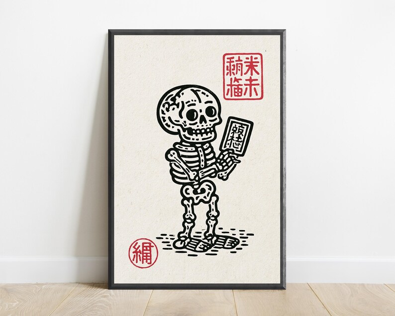 May include: A framed art print featuring a black ink illustration of a skeleton holding a small rectangular tablet. The design includes red square and circular stamps with Asian characters, set against a light cream-colored background.