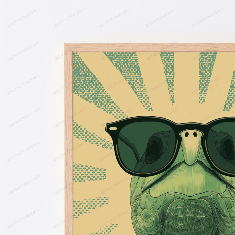 May include: A framed wall art print featuring a green turtle wearing black sunglasses. The background consists of a light yellow field with radiating green dotted sunburst lines. The frame is made of light-colored wood with a visible grain texture.