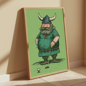 Puede incluir: Una l&aacute;mina art&iacute;stica enmarcada con una ilustraci&oacute;n de dibujos animados de un vikingo barbudo con casco de cuernos y t&uacute;nica verde, de pie sobre un campo de hierba mientras sostiene un palo de golf y se prepara para golpear una pelota de golf.