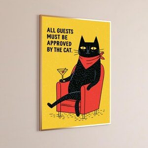 May include: A rectangular wall art print featuring a black cat wearing a red bandana, sitting in a red armchair while holding a martini glass. The yellow background includes the black text: ALL GUESTS MUST BE APPROVED BY THE CAT.