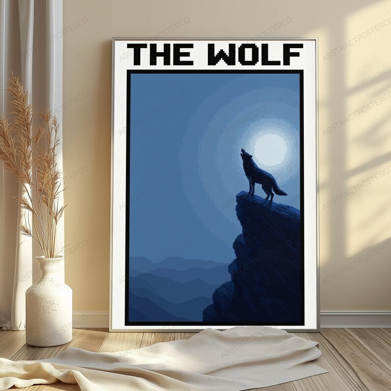 May include: A framed wall art print titled THE WOLF in a pixelated font. The image depicts a dark blue silhouette of a wolf standing on a rocky cliff, howling at a large, bright, circular moon against a deep blue night sky with mountain ranges.