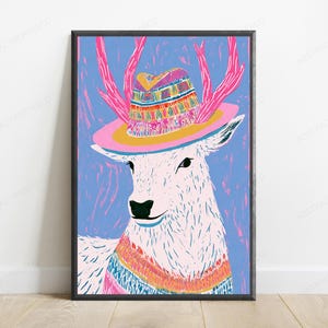 K&ouml;nnte beinhalten: Ein gerahmter Kunstdruck, der einen stilisierten wei&szlig;en Hirsch mit rosa Geweih zeigt, der einen bunten gemusterten Hut mit breiter gelber Krempe tr&auml;gt. Der Hirsch ist vor einem strukturierten blauen Hintergrund abgebildet und tr&auml;gt einen passenden gemusterten Pullover um den Hals.