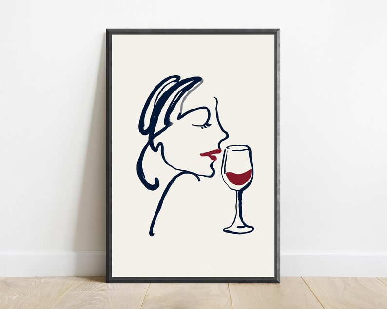 May include: A framed wall art print featuring a minimalist dark blue line drawing of a profile of a face with red lips, positioned next to a dark blue line drawing of a wine glass filled with red liquid, all set against a cream background.