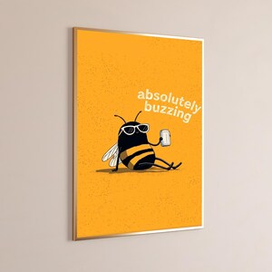 May include: A rectangular wall art print featuring a yellow background with a textured surface. A cartoon bee wearing white-rimmed sunglasses sits while holding a silver can. The text "absolutely buzzing" is printed in white above the bee.