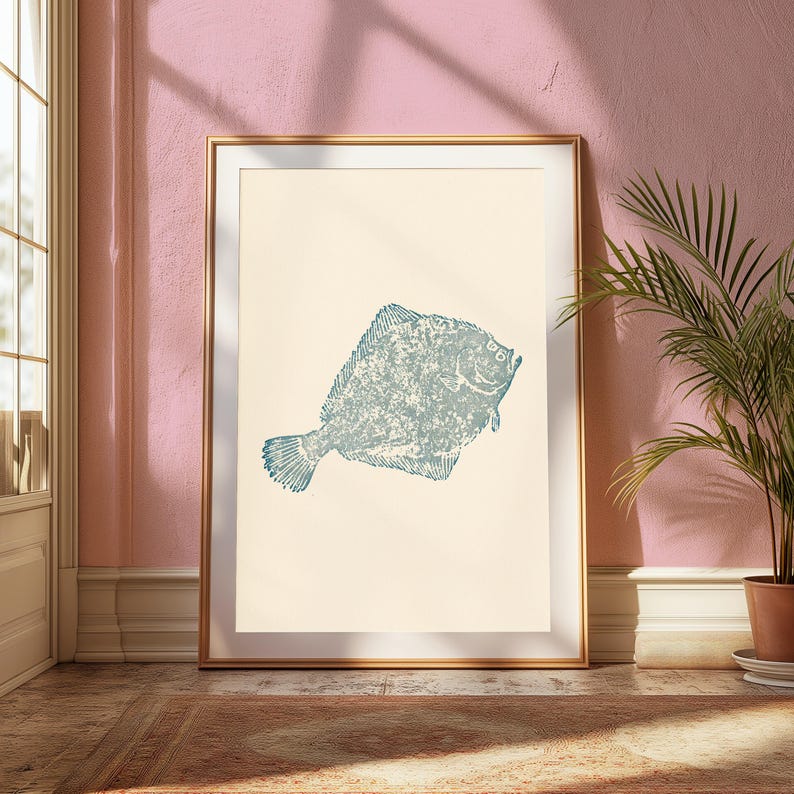 May include: A framed wall art print featuring a textured, blue-toned illustration of a flatfish centered on a cream-colored background. The artwork is enclosed in a thin, metallic gold frame, presenting a clean and simple visual composition.