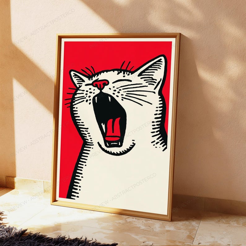 May include: A framed wall art print featuring a stylized white cat with black line details and a red nose, shown with its mouth wide open in a yawn. The cat is set against a solid red background, and the entire image is enclosed in a light wood frame.
