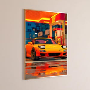 K&ouml;nnte beinhalten: Ein gerahmter Kunstdruck, der einen leuchtend orangefarbenen Sportwagen mit Klappscheinwerfern an einer Tankstelle unter einem gelben Vordach zeigt. Die Szene stellt einen regnerischen Abend mit Spiegelungen auf dem nassen Boden dar.