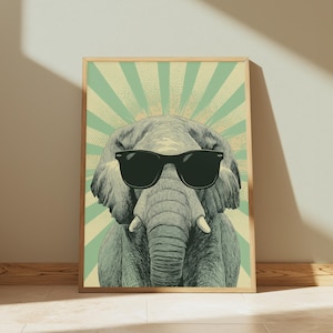 May include: A framed wall art print featuring a detailed illustration of a grey elephant wearing black sunglasses. The background consists of a light green and cream-coloured sunburst pattern with a stippled texture effect behind the elephant.