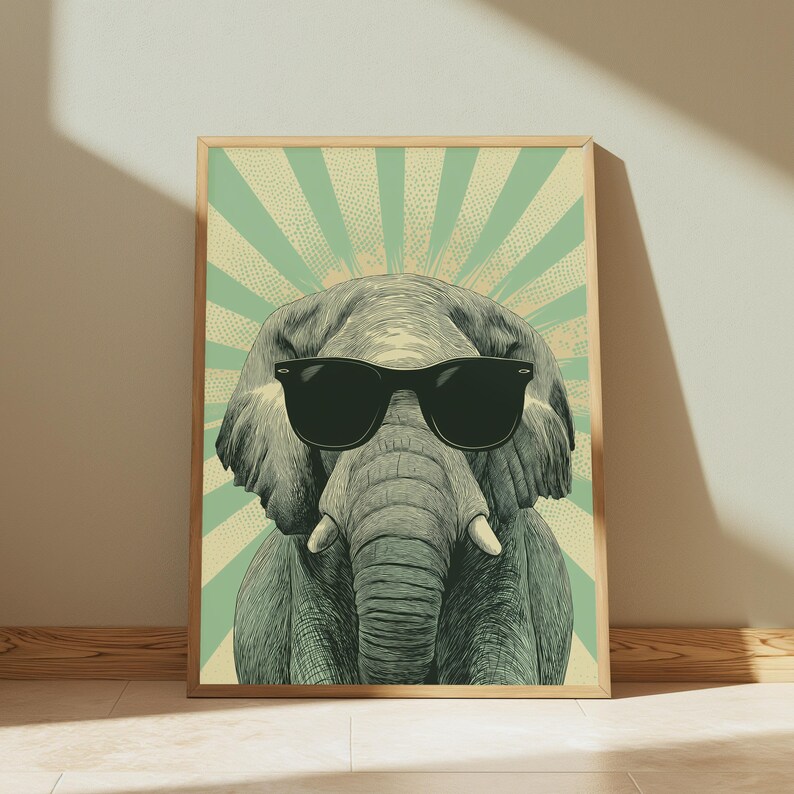 May include: A framed wall art print featuring a detailed illustration of a grey elephant wearing black sunglasses. The background consists of a light green and cream-coloured sunburst pattern with a stippled texture effect behind the elephant.