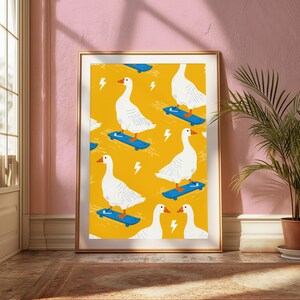 May include: A framed wall art print featuring a repeating pattern of white geese with orange beaks and feet riding blue skateboards on a vibrant yellow background, interspersed with small white lightning bolt icons throughout the design.