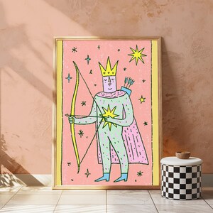 K&ouml;nnte beinhalten: Ein gerahmter Kunstdruck mit einer stilisierten Illustration einer Figur mit Krone und Umhang, die einen gelben Bogen und Pfeil h&auml;lt. Die Figur befindet sich vor einem rosa Hintergrund mit verstreuten gelben Sternen und blauen Akzenten, umrandet von einem gelben Rahmen.