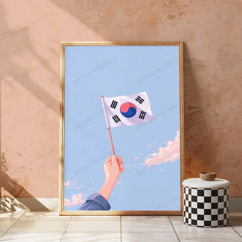 May include: A framed vertical poster featuring an illustration of a hand holding a South Korean flag against a light blue sky with soft pink clouds. The flag displays the central red and blue taegeuk symbol surrounded by four black trigrams.