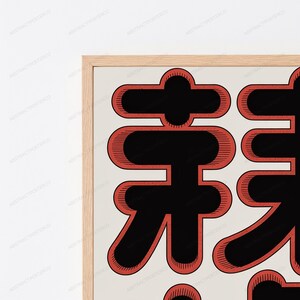 May include: A framed wall art print featuring large, bold black Japanese characters outlined in a thick, textured red border. The artwork is set against a light cream background and encased in a light-toned wooden frame with a clean, simple edge.