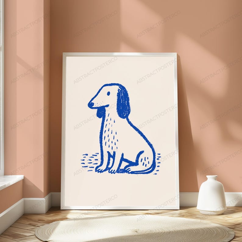 May include: A rectangular framed wall art print featuring a simple blue line drawing of a seated dog on a light beige background. The dog illustration has a textured, hand-drawn appearance with visible strokes, positioned centrally within the white frame.