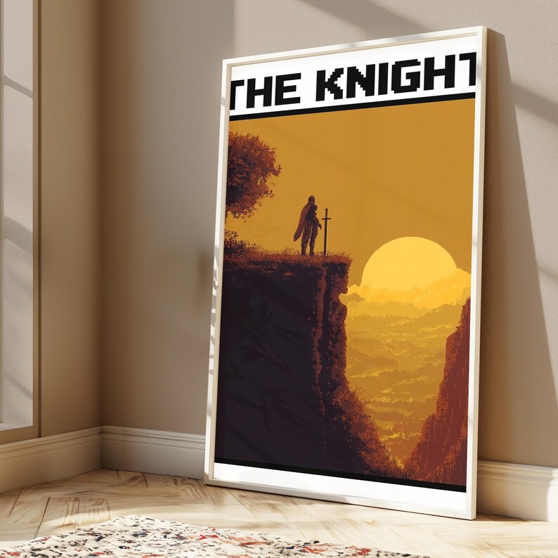 May include: A framed vertical poster featuring a pixel art illustration of a knight standing on a cliff edge with a sword, overlooking a valley at sunset. The text THE KNIGHT is printed in a bold, black, pixelated font at the top of the print.