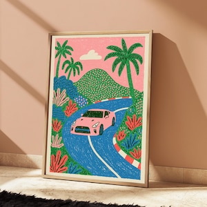 May include: A framed art print featuring a stylised illustration of a pink sports car driving along a winding blue road. The scene includes green palm trees, a dotted green mountain, and a small white cloud set against a solid pink sky background.