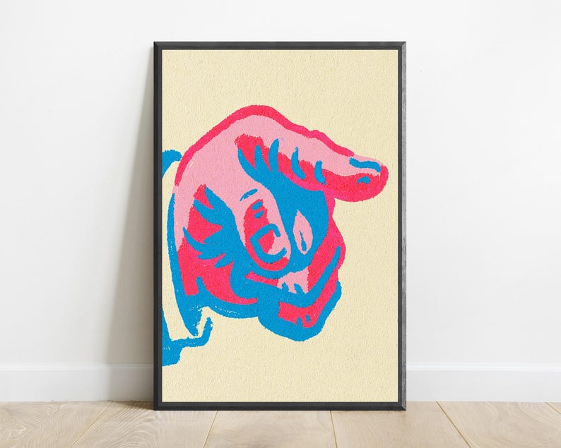 May include: A framed wall art print featuring a stylised graphic of a hand pointing to the right. The design uses a bold colour palette of bright pink and vibrant blue against a textured, pale cream-coloured background within a thin black frame.