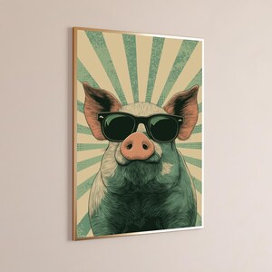 May include: A framed wall art print featuring a stylised illustration of a pig wearing black sunglasses. The pig is centred against a background of radiating light green and beige sunburst stripes with a subtle dotted halftone texture pattern.
