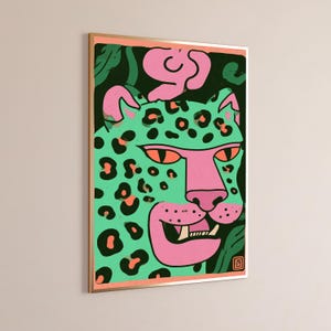 May include: A framed rectangular wall art print featuring a stylized leopard head in mint green with pink accents and black spots. The leopard has orange eyes, a pink snout, and visible teeth. The background is dark green with pink shapes.