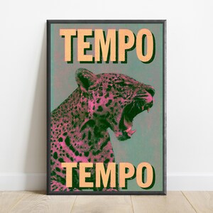 Pu&ograve; includere: Una stampa artistica rettangolare incorniciata raffigurante un leopardo ruggente in punti mezzatinta rosa e neri su uno sfondo verde acqua tenue. La parola TEMPO &egrave; stampata in grandi lettere maiuscole arancioni chiare in alto e in basso.