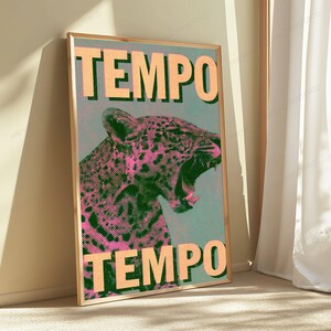 Pu&ograve; includere: Un poster rettangolare incorniciato raffigurante un leopardo stilizzato con la bocca aperta, reso con un motivo a punti mezzitoni rosa e verde scuro. La parola TEMPO &egrave; stampata in grandi lettere arancione chiaro sia nella parte superiore che inferiore.