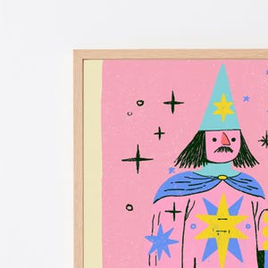Może przedstawiać: Oprawiony wydruk artystyczny przedstawiający stylizowaną ilustrację czarodzieja na r&oacute;żowym tle. Czarodziej ma na sobie jasnoniebieski spiczasty kapelusz i pelerynę, ozdobione ż&oacute;łtymi i niebieskimi gwiazdami. Czarne kontury podkreślają postać.