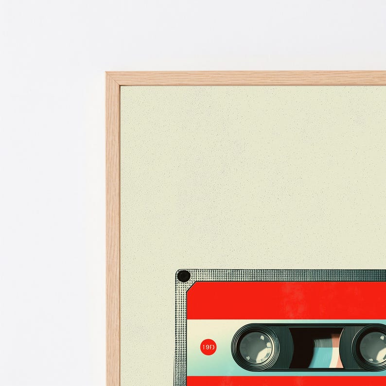 May include: A framed wall art print featuring a graphic illustration of a red cassette tape with a light cream background. The cassette tape includes two circular spools, a central window, and a small red circle with the text 19F inside.